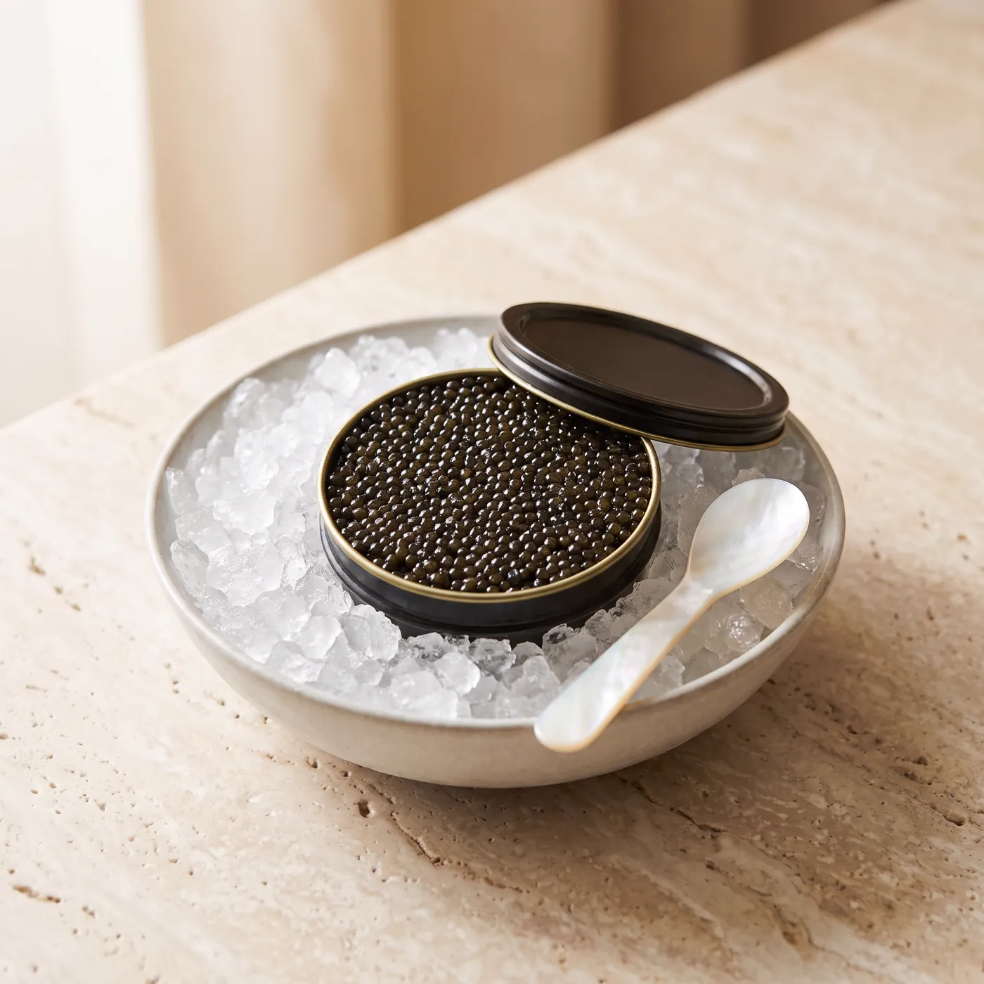 An open tin of black caviar on crushed ice in a white bowl, with a mother-of-pearl spoon.